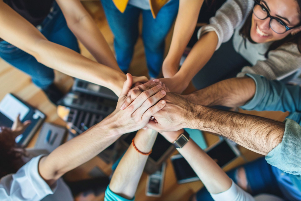 Ensemble pour réussir : la force de l'engagement en apprentissage Un groupe de jeunes et de formateurs lèvent leurs mains empilées en un geste de cohésion et de motivation. L'image symbolise l'esprit d'équipe et l'engagement collectif en apprentissage.