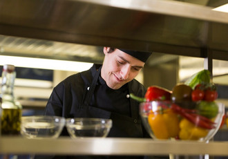 Un apprenti cuisinier en train de cuisiner un plat.