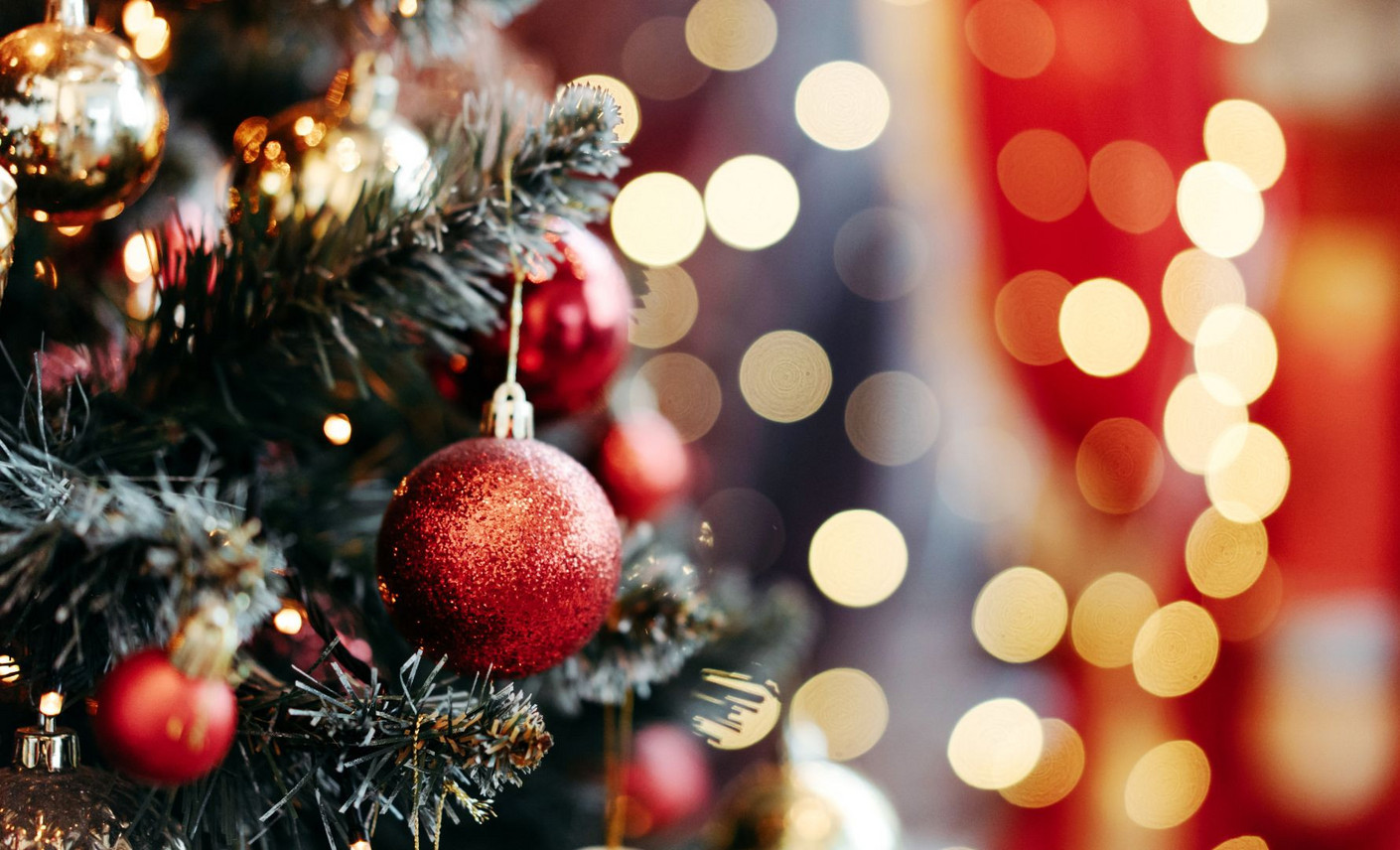 Apprentis, offrez des cadeaux faits main uniques pour des fêtes inoubliables Un sapin décoré de boules artisanales et de guirlandes scintillantes, avec un flou d'arrière-plan lumineux évoquant la chaleur des fêtes de fin d'année