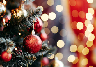 Apprentis, offrez des cadeaux faits main uniques pour des fêtes inoubliables Un sapin décoré de boules artisanales et de guirlandes scintillantes, avec un flou d'arrière-plan lumineux évoquant la chaleur des fêtes de fin d'année