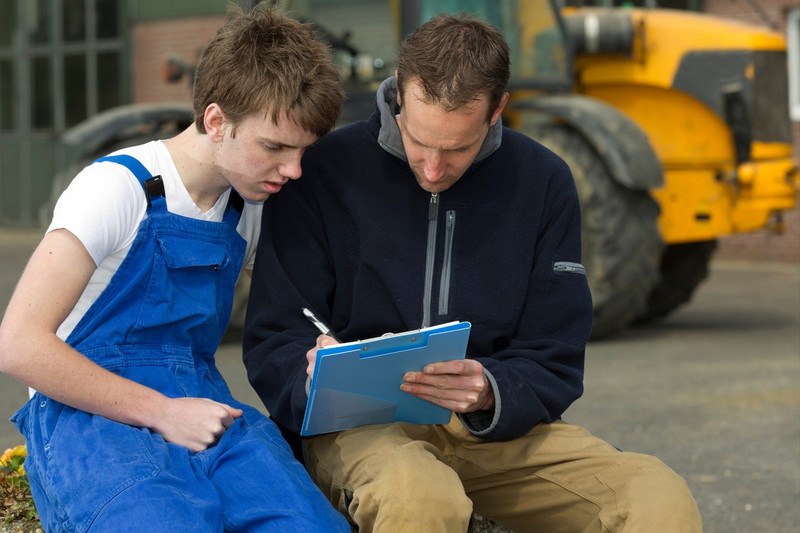 Apprenti agriculteur apprenant à utiliser une machine agricole avec son tuteur Maîtriser les machines agricoles par le biais de l'apprentissage
